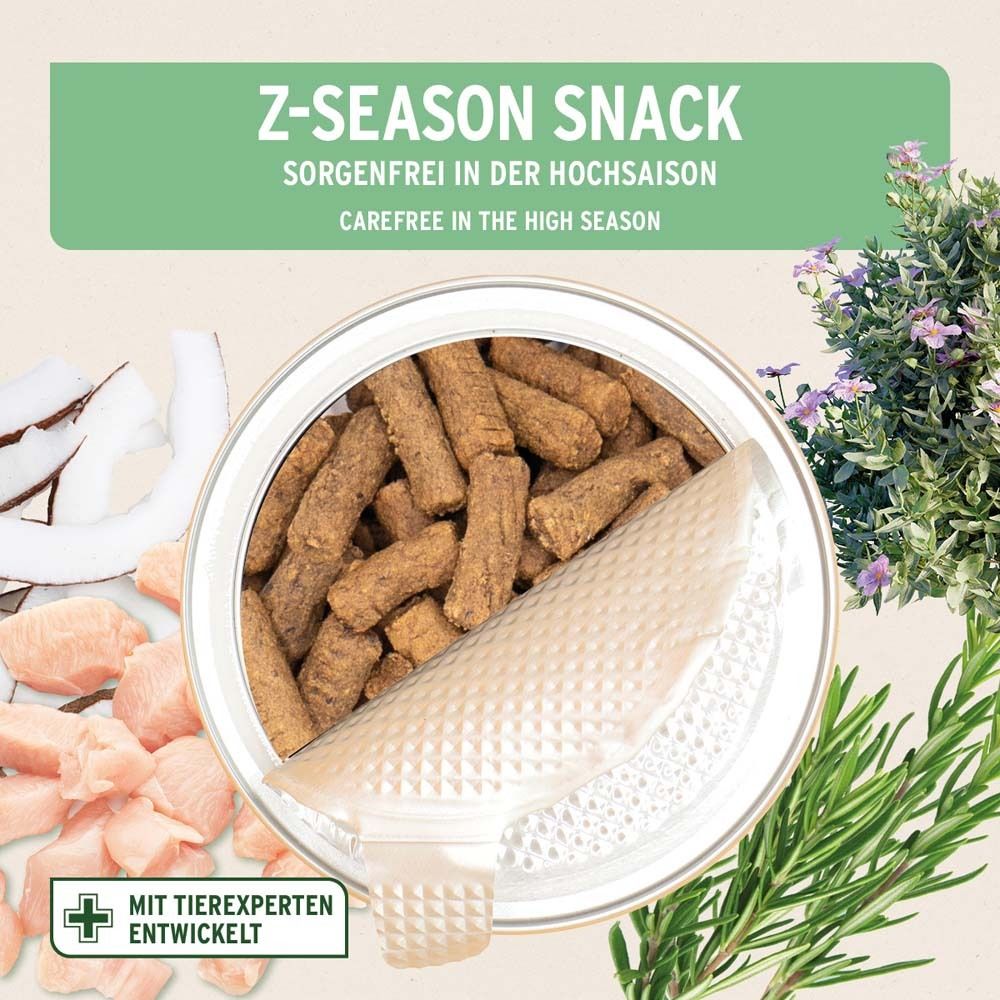 Boîte ouverte avec Z-Season Snack. Snacks bruns et allongés. Noix de coco, poulet et herbes en décoration.