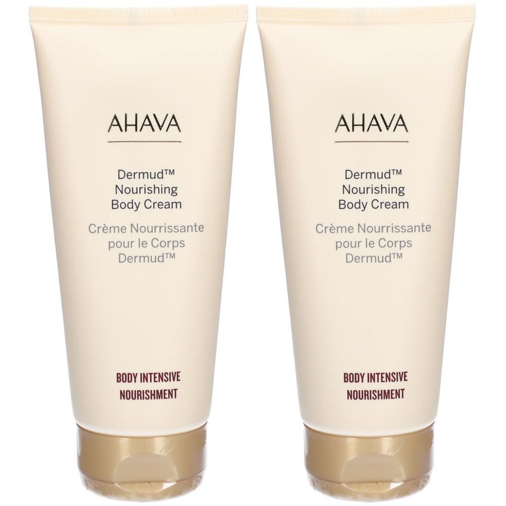 Zwei Tuben AHAVA Dermud Nourishing Body Cream. Beige Tuben mit goldfarbenen Verschlüssen. Schriftzug: AHAVA, Dermud, Body Cream.