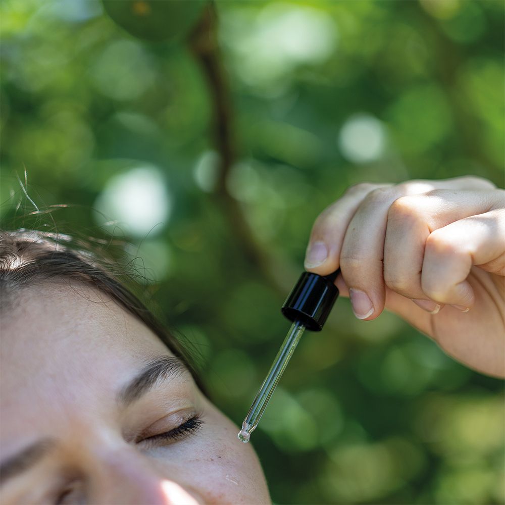 Nahaufnahme eines Gesichts. Pipette tropft Serum auf die Haut. 