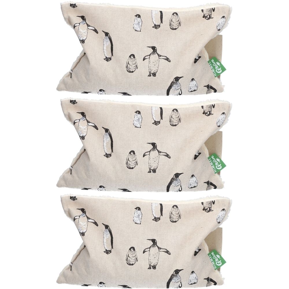 Drei Kirschkernkissen mit Pinguin-Muster. Beige Stoff mit schwarzen Pinguin-Illustrationen. Grün-weiße Etiketten.