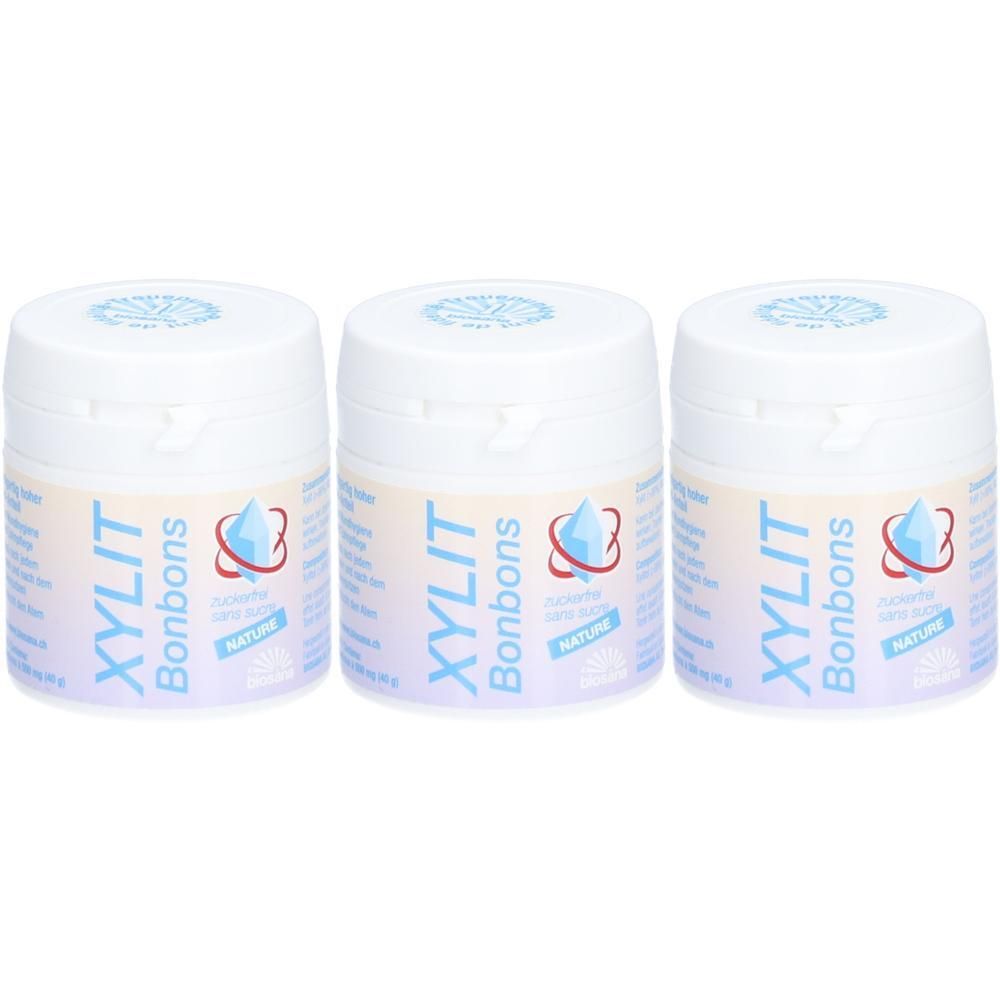 Trois pots blancs avec l'inscription bleue XYLIT Bonbons. Logo Nature et informations produit.