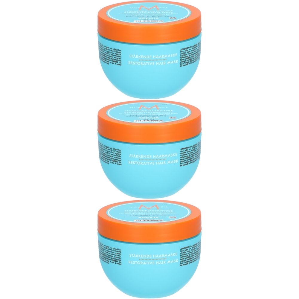 Trois pots turquoise avec des couvercles orange. On peut lire "Stärkende Haarmaske" et "Restorative Hair Mask" sur les pots.
