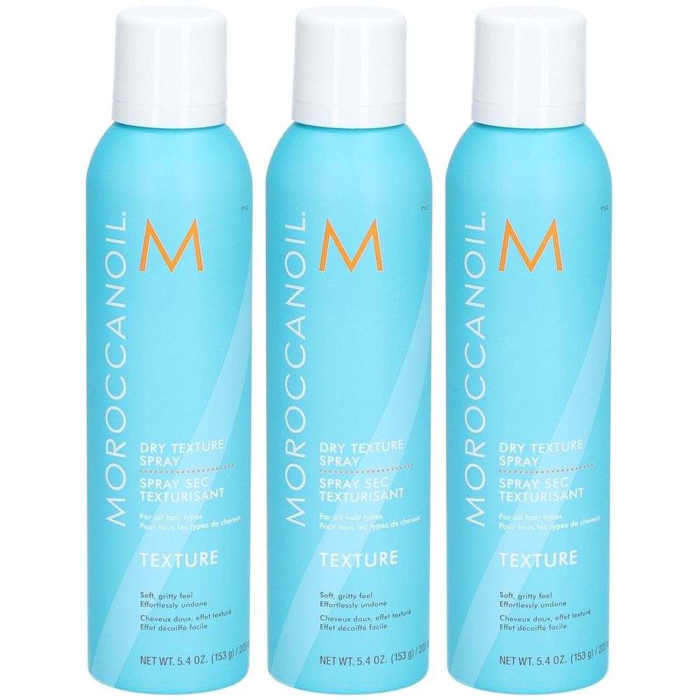 Trois flacons de spray bleus avec bouchons blancs. Inscription : Moroccanoil, Dry Texture Spray. Spray texturisant pour tous types de cheveux.