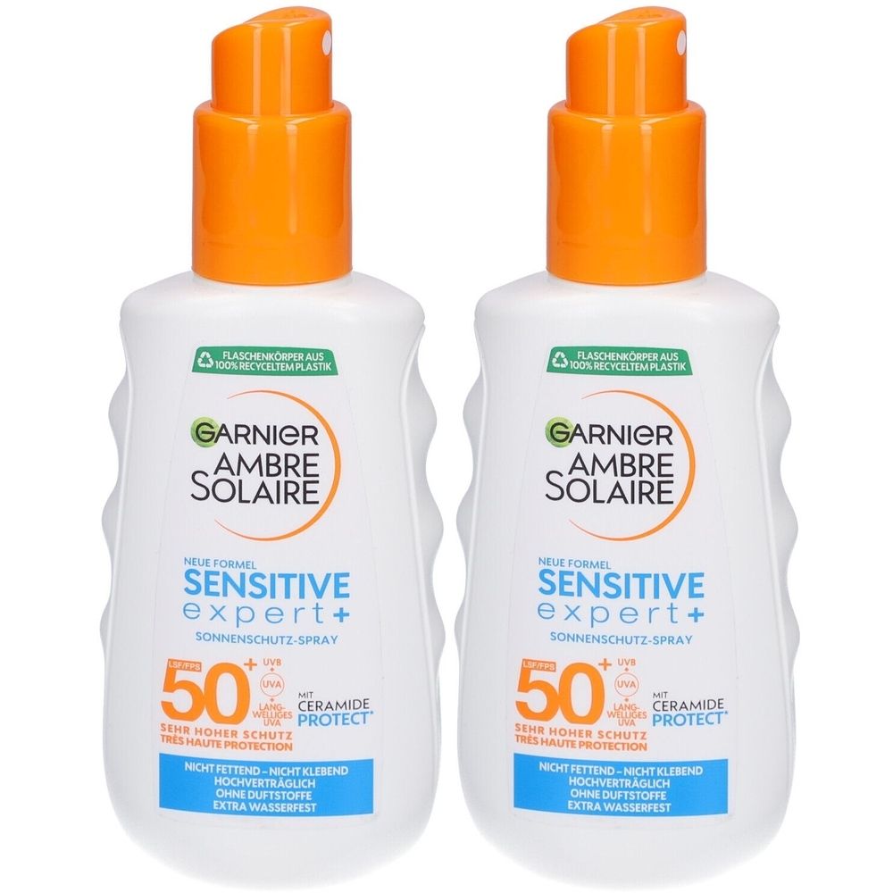 Zwei Flaschen Garnier Ambre Solaire Sensitive Expert+ Sonnenschutz-Spray SPF50+. Weiße Flaschen mit orangefarbenen Sprühköpfen.