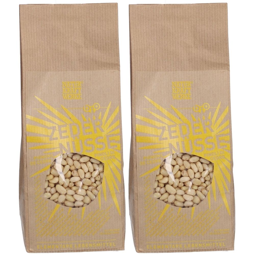 Zwei Beutel mit Zedernüssen. Braune Papiertüten mit Sichtfenster. Gelber Aufdruck mit Schriftzug "ZEDER NÜSSE".