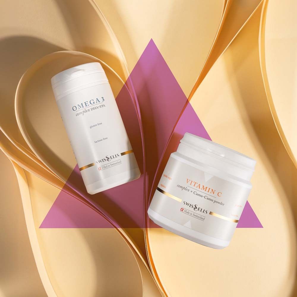 Zwei weiße Behälter: Omega 3 und Vitamin C. Goldfarbene Akzente. Logo Swissells. Rosa und goldfarbener Hintergrund.