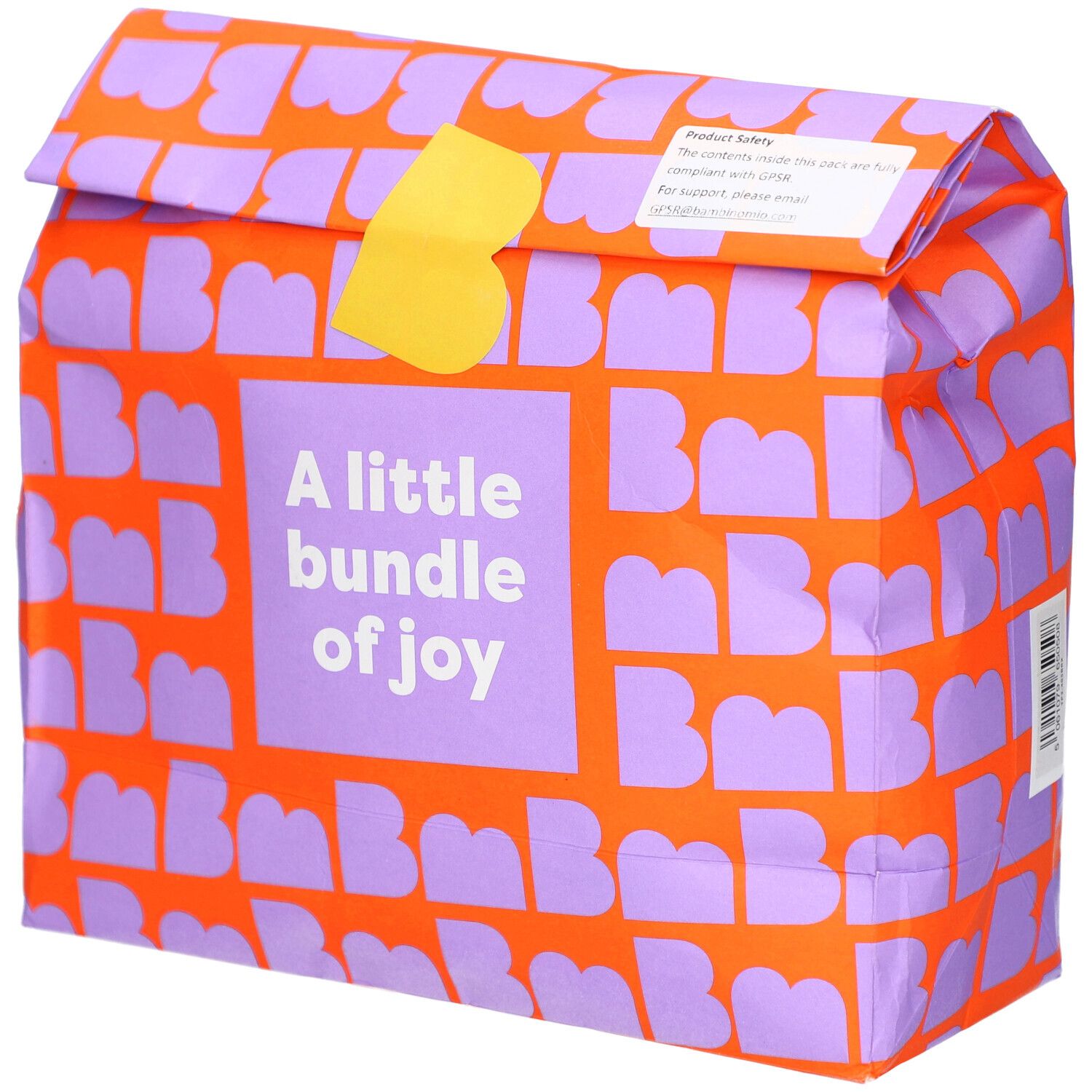 Verpackung mit orangefarbenem Muster und lila Buchstaben. Aufschrift: A little bundle of joy. Gelber Verschluss.