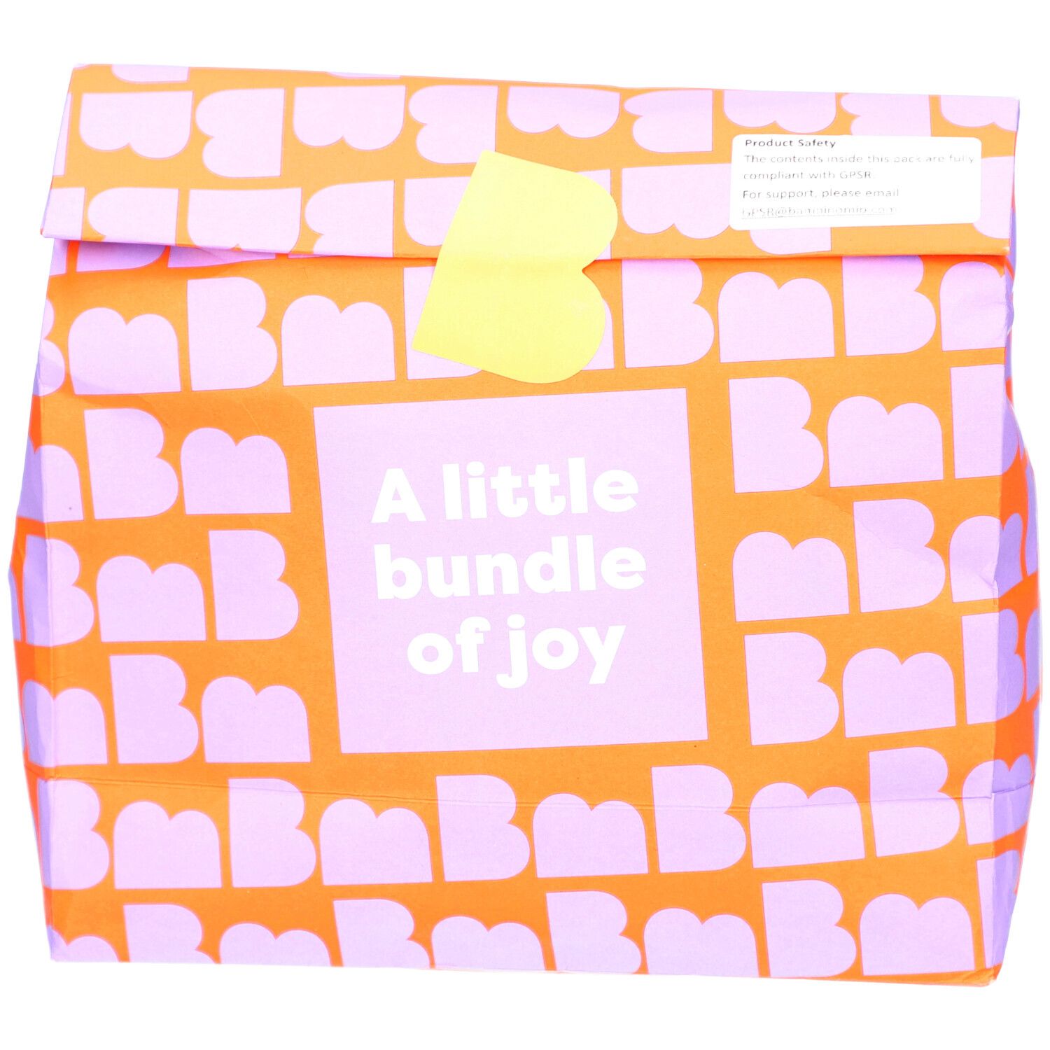 Verpackung mit orangefarbenem Muster und lila Buchstaben. Aufschrift: A little bundle of joy. Gelber Verschluss.