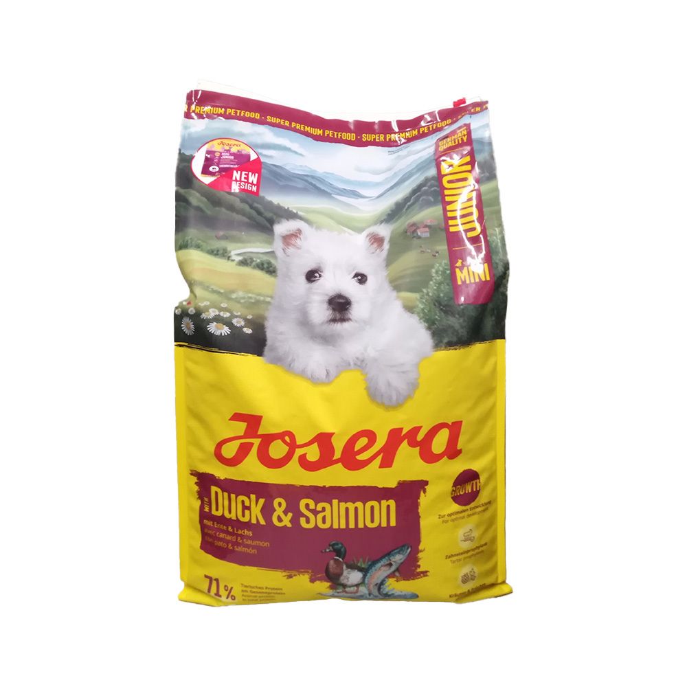 Gelber Beutel mit Aufdruck. Enthält Futter für Hunde. Aufschrift: Josera, Duck & Salmon, Junior Mini. Ein Welpe schaut heraus.