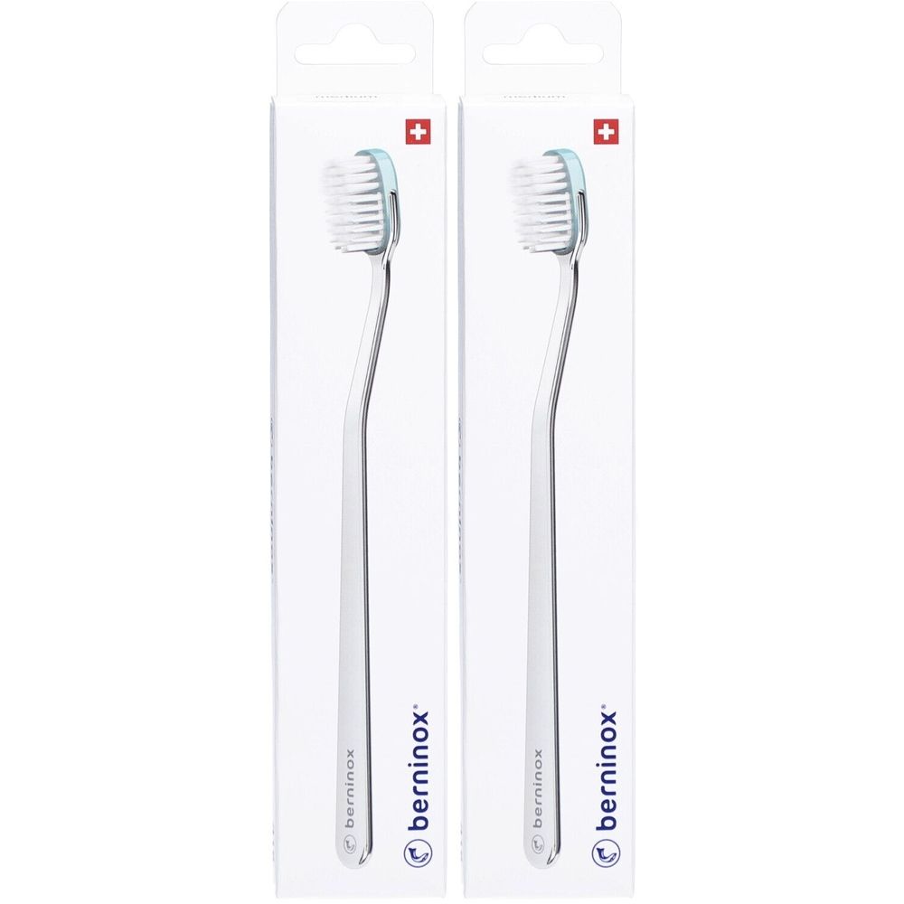 Zwei Zahnbürsten in Verpackung. Weiße Borsten, hellgrüner Bürstenkopf, transparenter Griff. Schweizer Kreuz. Marke: berninox.
