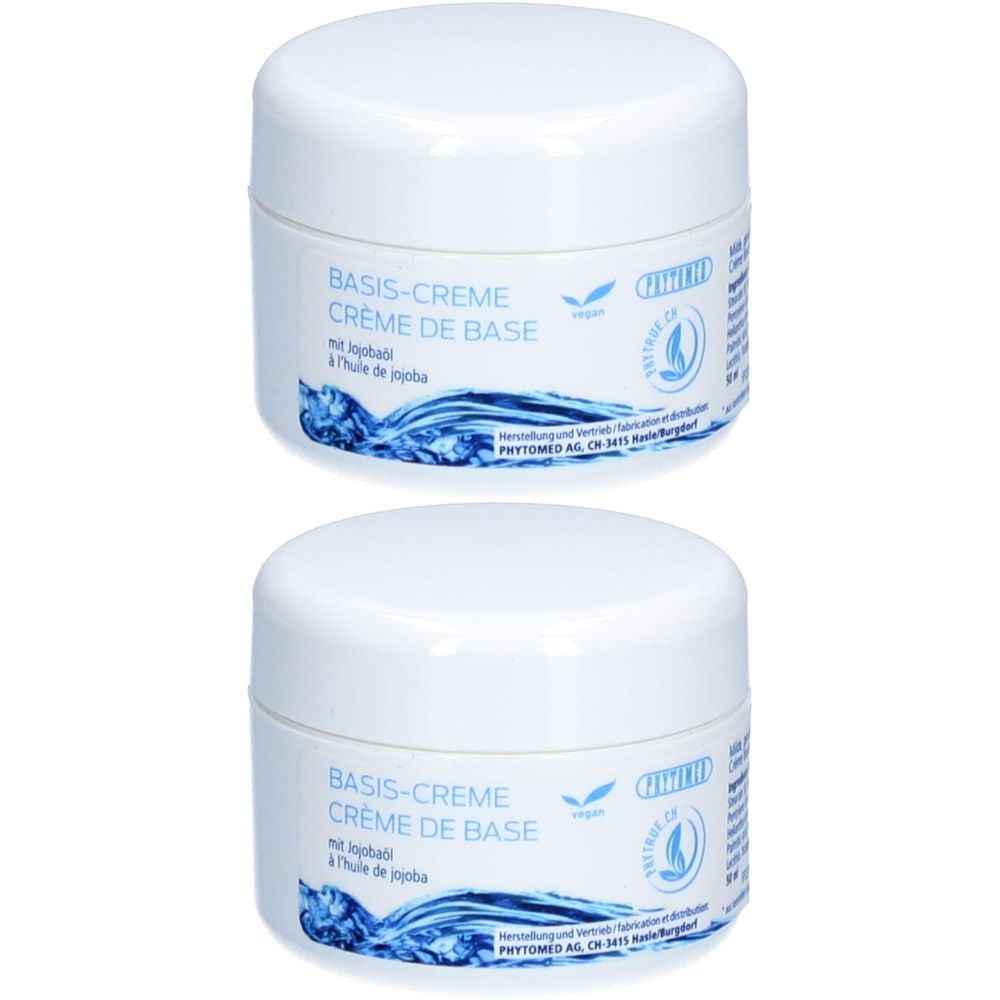 Deux pots blancs avec couvercles. Inscription: BASIS-CREME, CRÈME DE BASE. Avec huile de jojoba. Logo végan. Logo PHYTOMED.