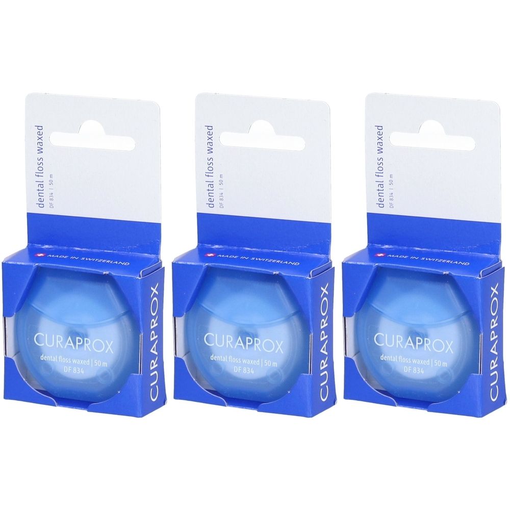 Drei Packungen Zahnseide. Blaue, runde Behälter in blauen Kartons mit weißem Aufhänger. Marke CURAPROX sichtbar.