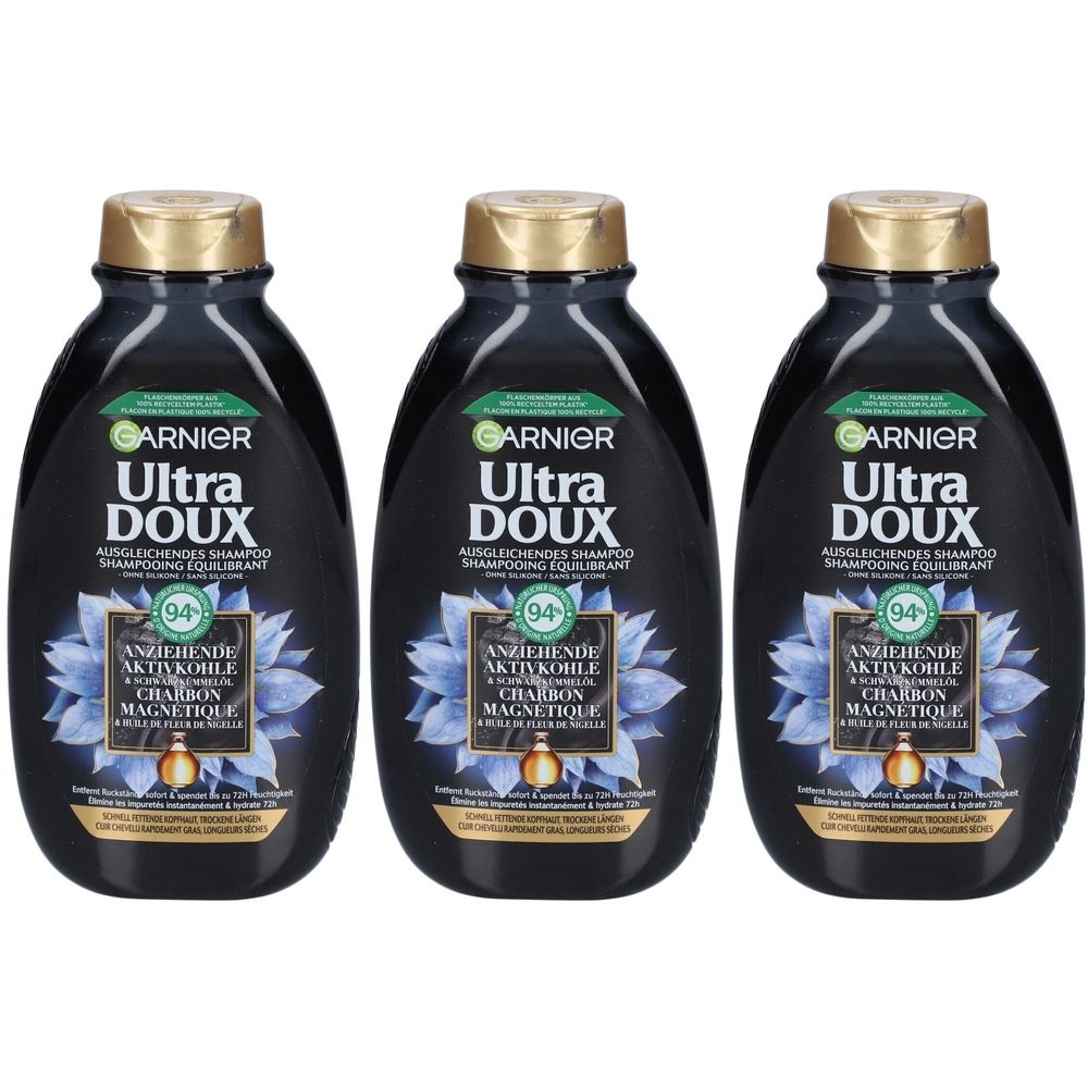 Trois flacons de shampooing noirs avec bouchons dorés. Inscription: Garnier Ultra Doux, Charbon Magnétique.