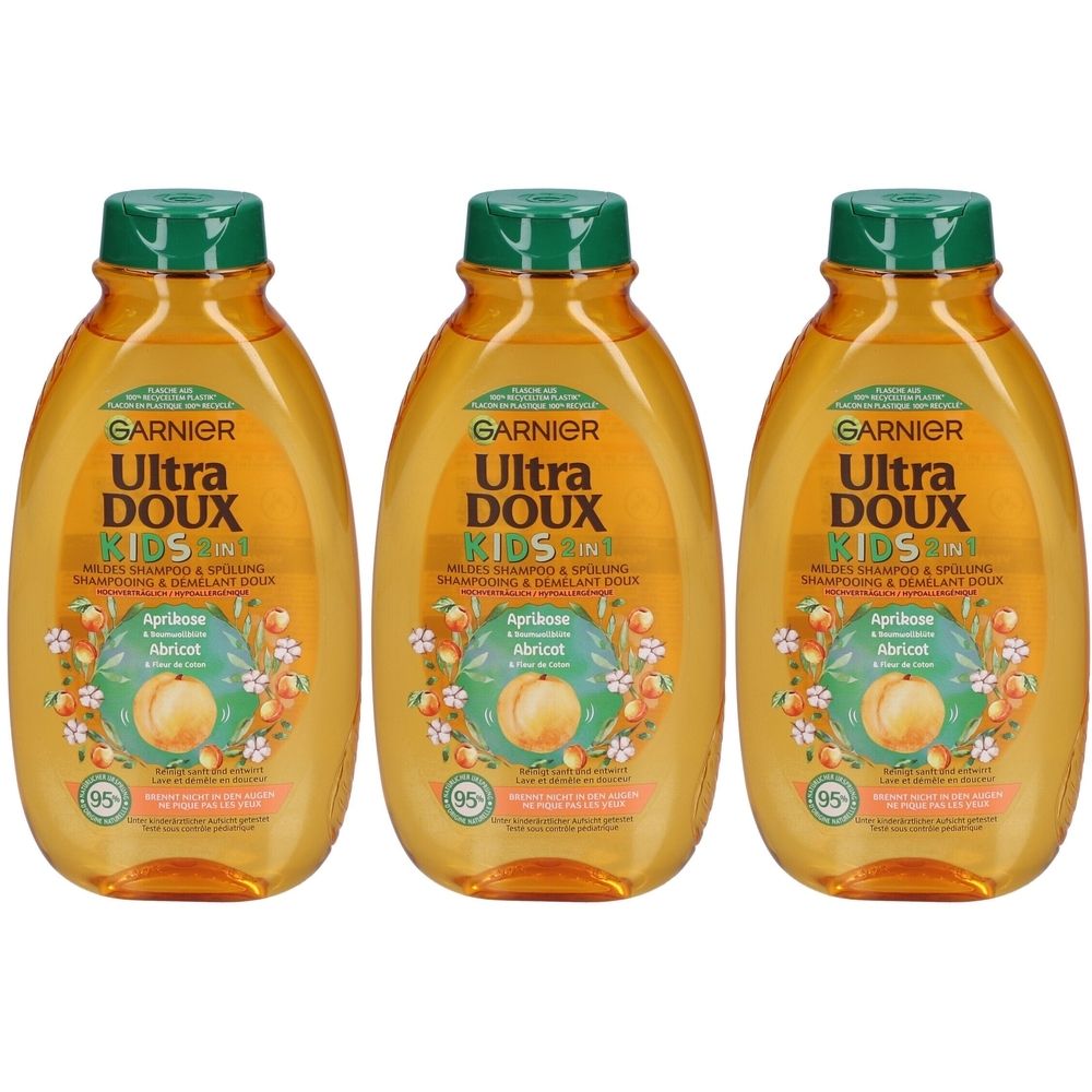 Drei Flaschen Garnier Ultra Doux Kids 2 in 1 Shampoo. Orangefarbene Flaschen mit grünem Deckel. Aufschrift: Aprikose, Abricot.