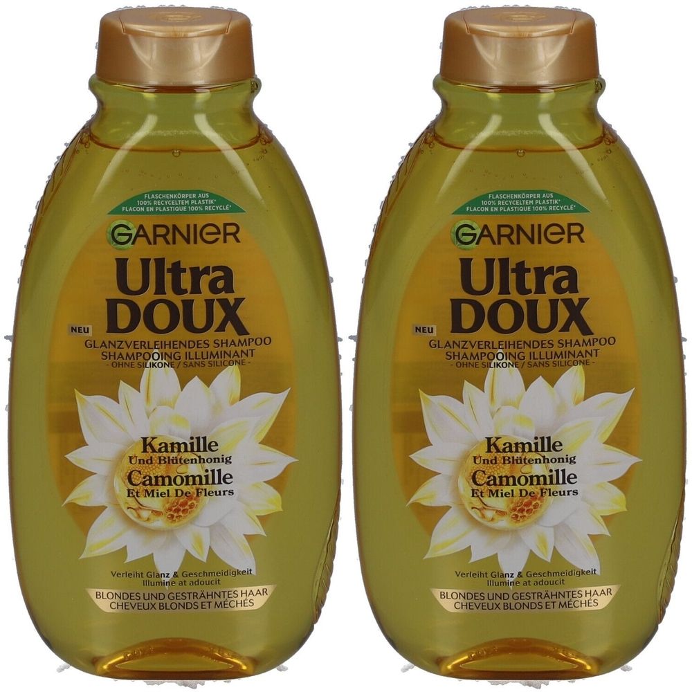 Zwei Flaschen Garnier Ultra Doux Shampoo. Goldfarbene Kappe, gelbliche Flüssigkeit. Aufschrift: Kamille und Blütenhonig. Für blondes Haar.