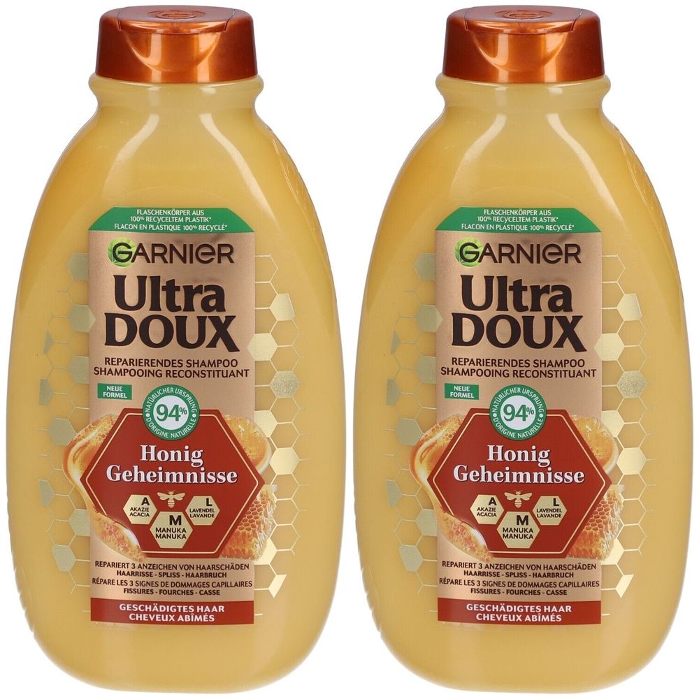 Deux flacons de shampooing réparateur Garnier Ultra Doux Honig Geheimnisse. Liquide jaune, bouchon marron, étiquette avec texte et logo.