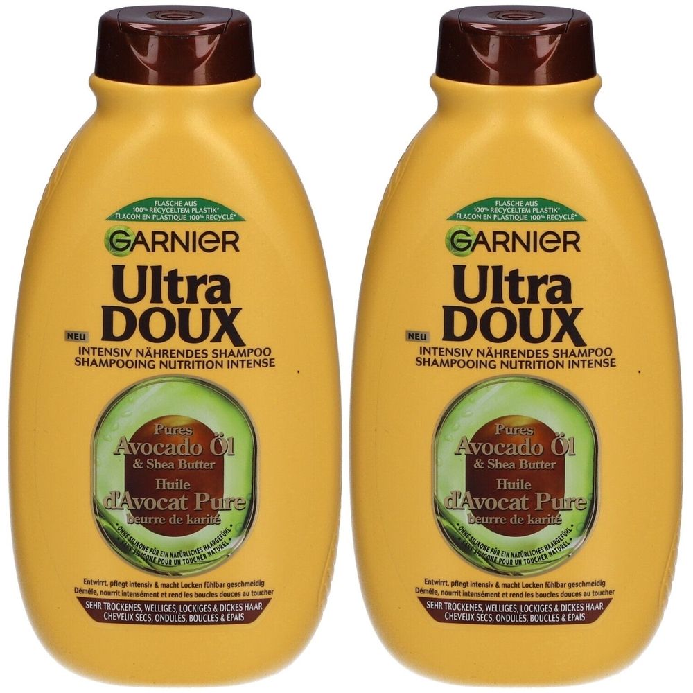 Deux flacons jaunes avec bouchons marron. Inscription: GARNIER Ultra DOUX, Huile d'Avocat & Beurre de Karité. Shampooing pour cheveux secs, ondulés, bouclés.