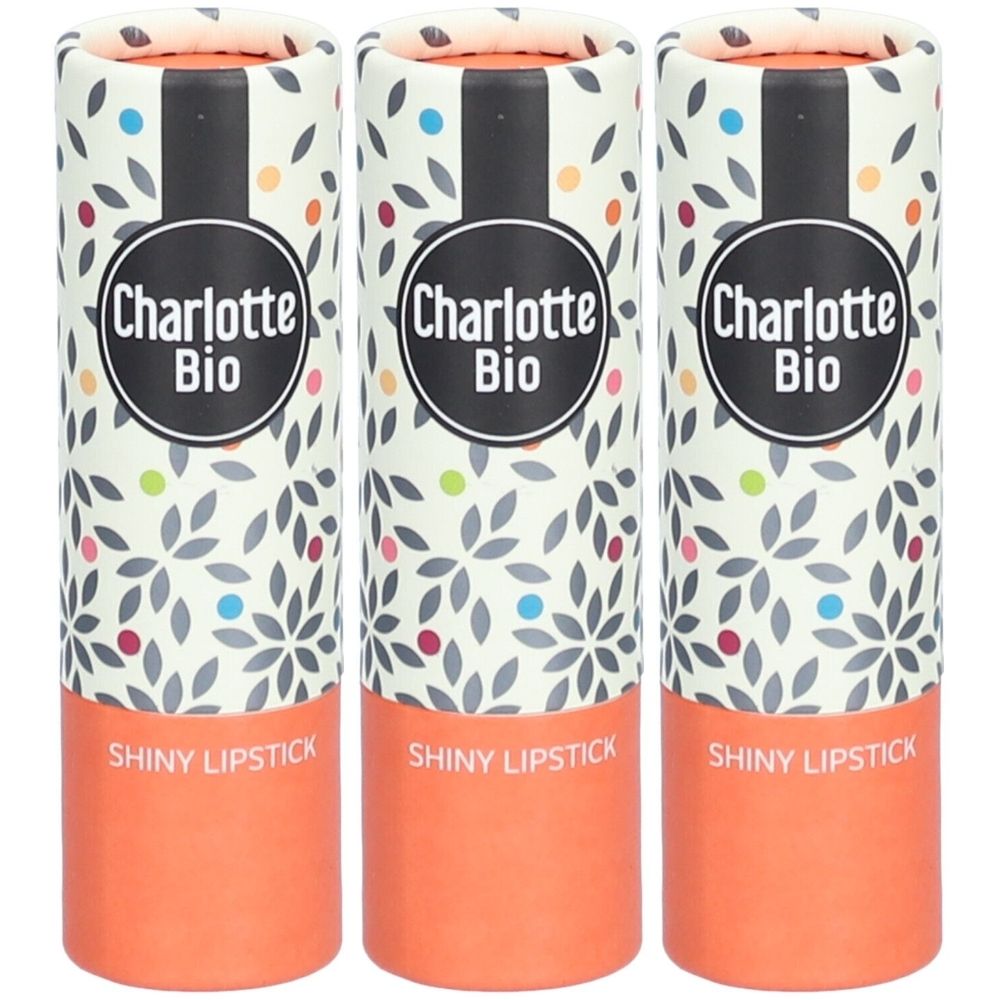 Trois emballages cylindriques de rouge à lèvres. Inscription "Charlotte Bio" et "Shiny Lipstick". Emballage à motifs floraux et base orange.