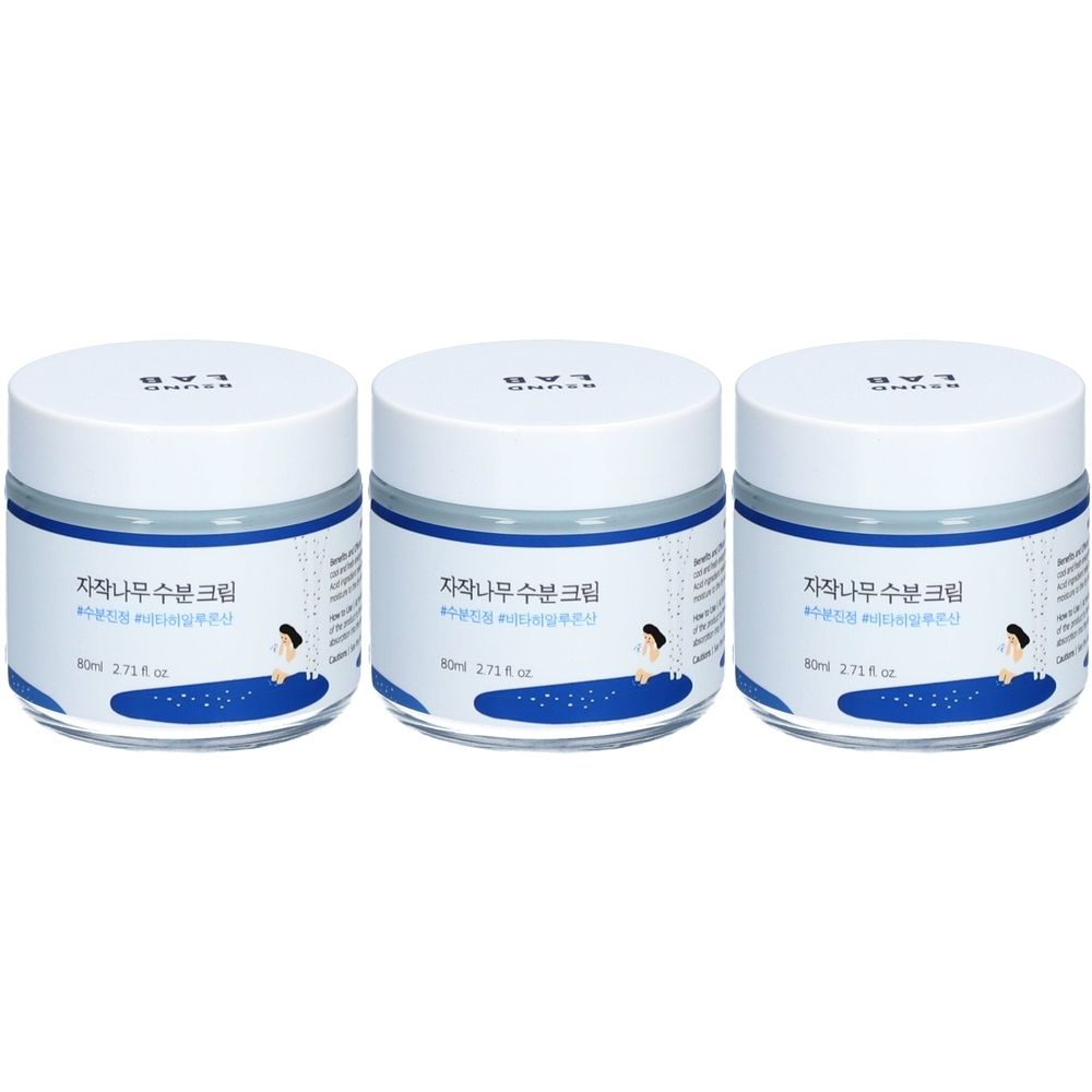 Trois pots blancs avec bordure et couvercle bleus. Texte coréen sur les étiquettes et inscription "ROUND LAB".