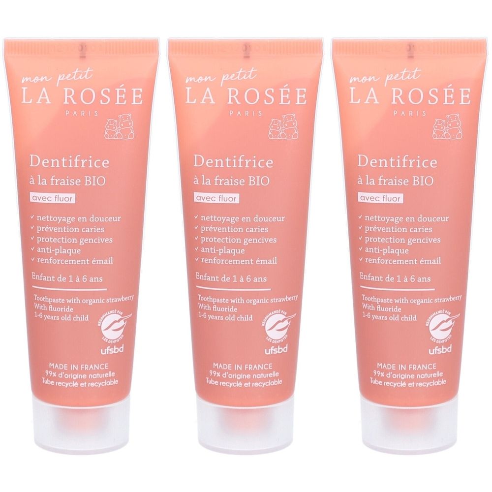 Trois tubes de dentifrice rose avec bouchon blanc. Inscription: "Dentifrice à la fraise BIO" avec fluor. Pour enfants de 1 à 6 ans.