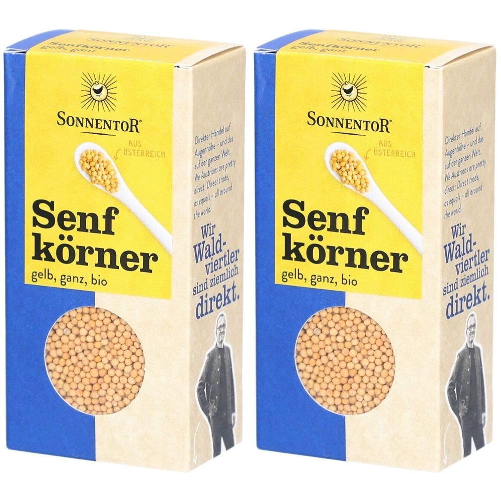 Zwei Kartons mit gelben Senfkörnern. Aufschrift: SONNENTOR, Senfkörner gelb, ganz, bio. Blaue und beige Verpackung.