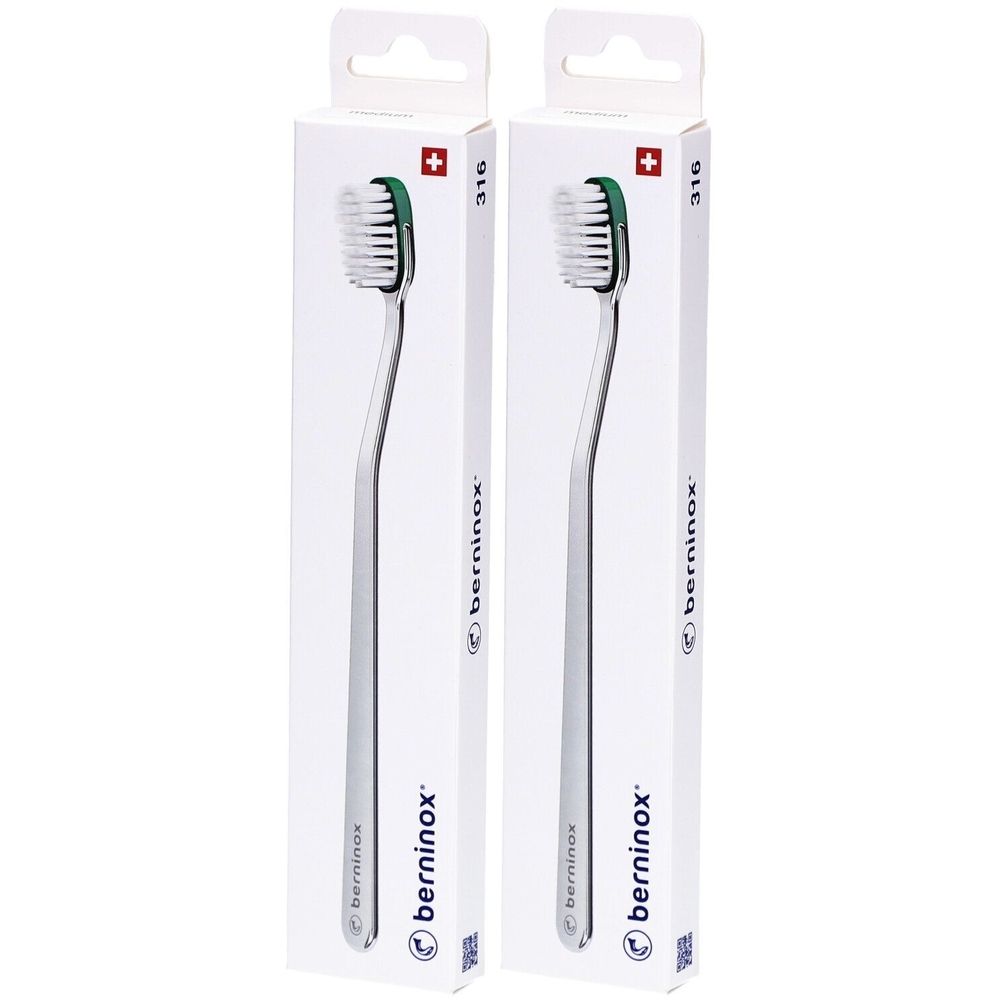 Deux brosses à dents dans leur emballage. Manche en métal, tête verte. Emballage avec croix suisse et texte.