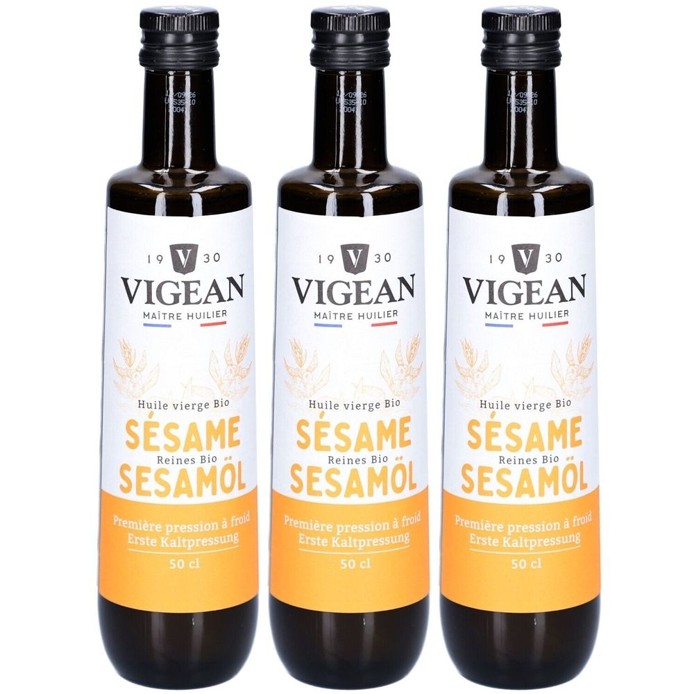 Drei Flaschen Vigean Bio Sesamöl. Schwarze Kappen, weiße Etiketten mit Schriftzug und gelbem Streifen. 50 cl.