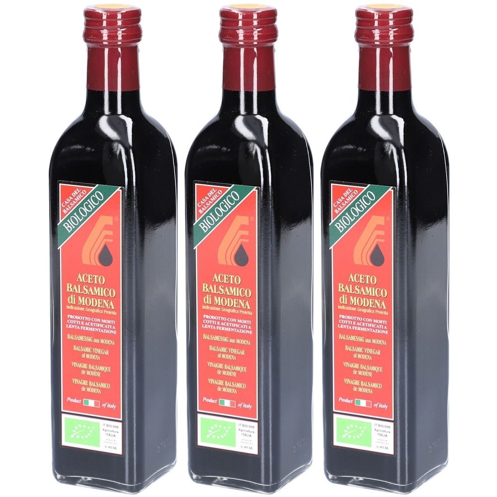 Trois bouteilles de vinaigre balsamique de Modène. Verre noir, bouchon rouge, étiquette rouge avec texte et logo.