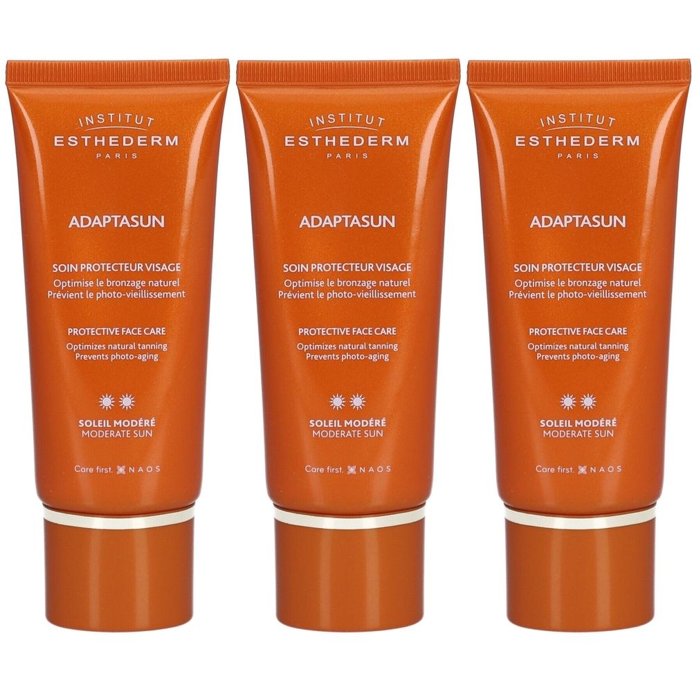 Trois tubes de crème visage Adaptasun. Tubes orange avec texte blanc. Inscriptions: INSTITUT ESTHEDERM, ADAPTASUN, SOIN PROTECTEUR VISAGE, SOLEIL MODERE.