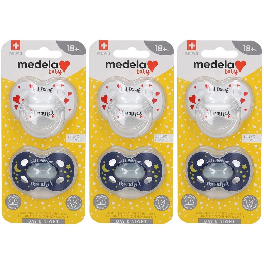 Trois sucettes Medela Baby emballées. En haut, blanc avec des cœurs rouges, en bas, bleu avec lune et étoiles. Recommandé pour 18+ mois.