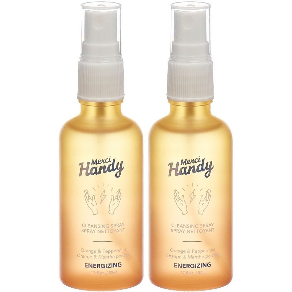 Zwei goldfarbene Sprühflaschen. Aufschrift: Merci Handy, Cleansing Spray, Energizing. Mit Händen und Blitzen.