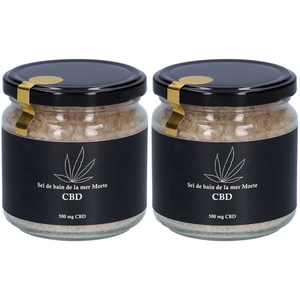 Deux pots de sel de bain. Étiquettes noires avec logo CBD et texte. Fermeture dorée. Inscription: Sel de bain de la mer Morte, CBD, 500 mg CBD.