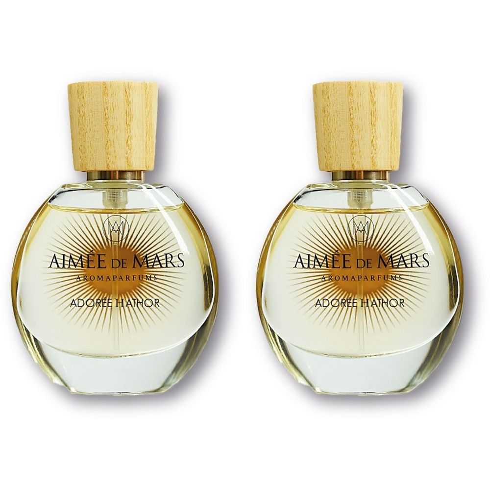 Zwei runde Glasflakons mit Holzdeckel. Aufschrift: AIMEE DE MARS AROMA PARFUMS, ADOREE HATHOR. Goldfarbene Details.