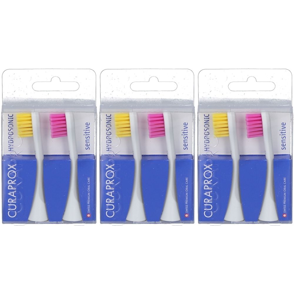 Drei Packungen mit Ersatzbürstenköpfen. Blaue Griffe, gelbe und pinkfarbene Borsten. Verpackung mit Produktnamen und Logo.