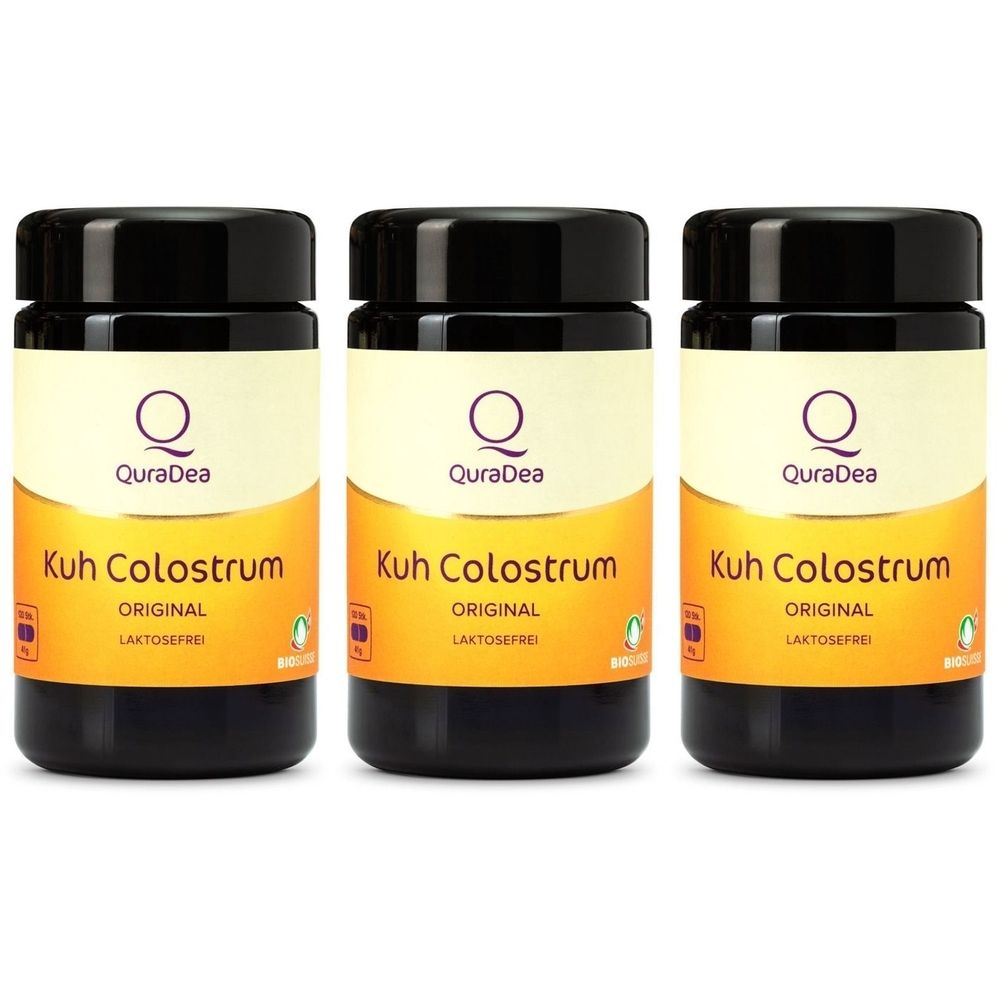 Drei braune Gläser mit schwarzem Deckel. Aufschrift: QuraDea, Kuh Colostrum Original, laktosefrei. Gelb-oranger Etikett.