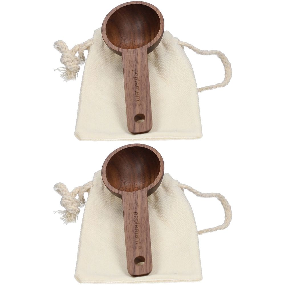 Zwei Holzlöffel mit rundem Löffelteil und langem Griff. Auf dem Griff steht "peplement". Sie liegen in Stoffbeuteln.