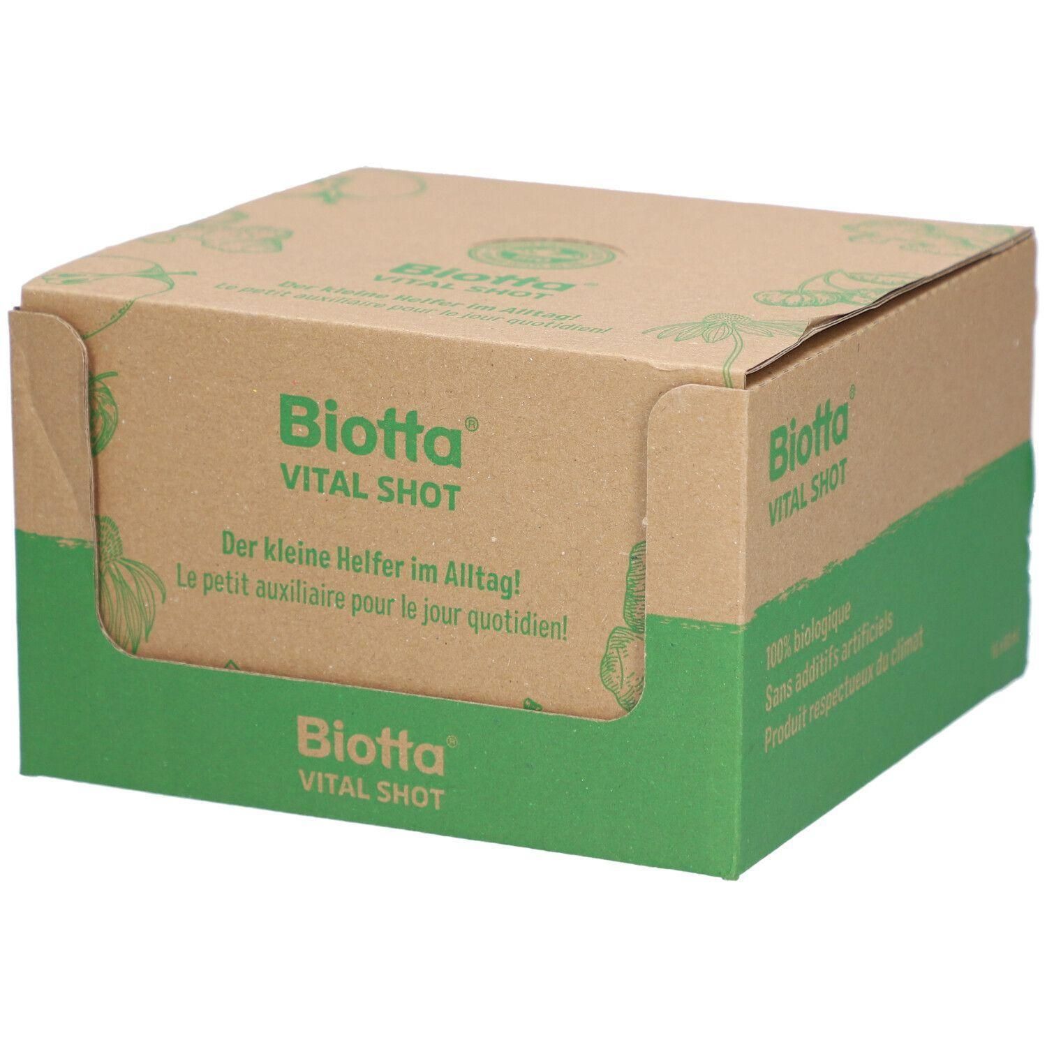 Emballage en carton avec le logo "Biotta Vital Shot". Texte : "Der kleine Helfer im Alltag!" et "Le petit auxiliaire pour le jour quotidien!"