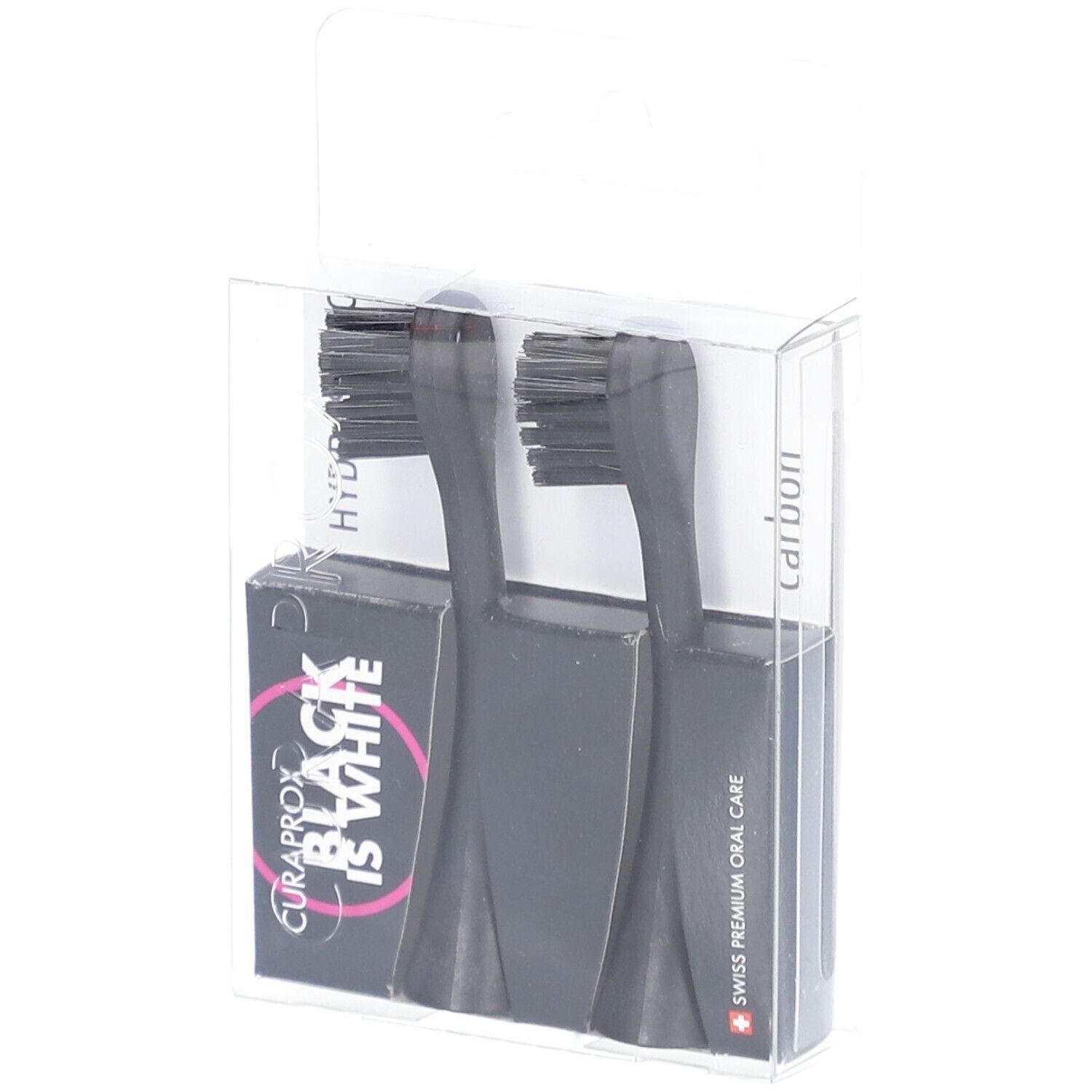 Deux têtes de brosse à dents noires dans un emballage transparent. L'emballage porte l'inscription "BLACK IS WHITE" et "Carbon".
