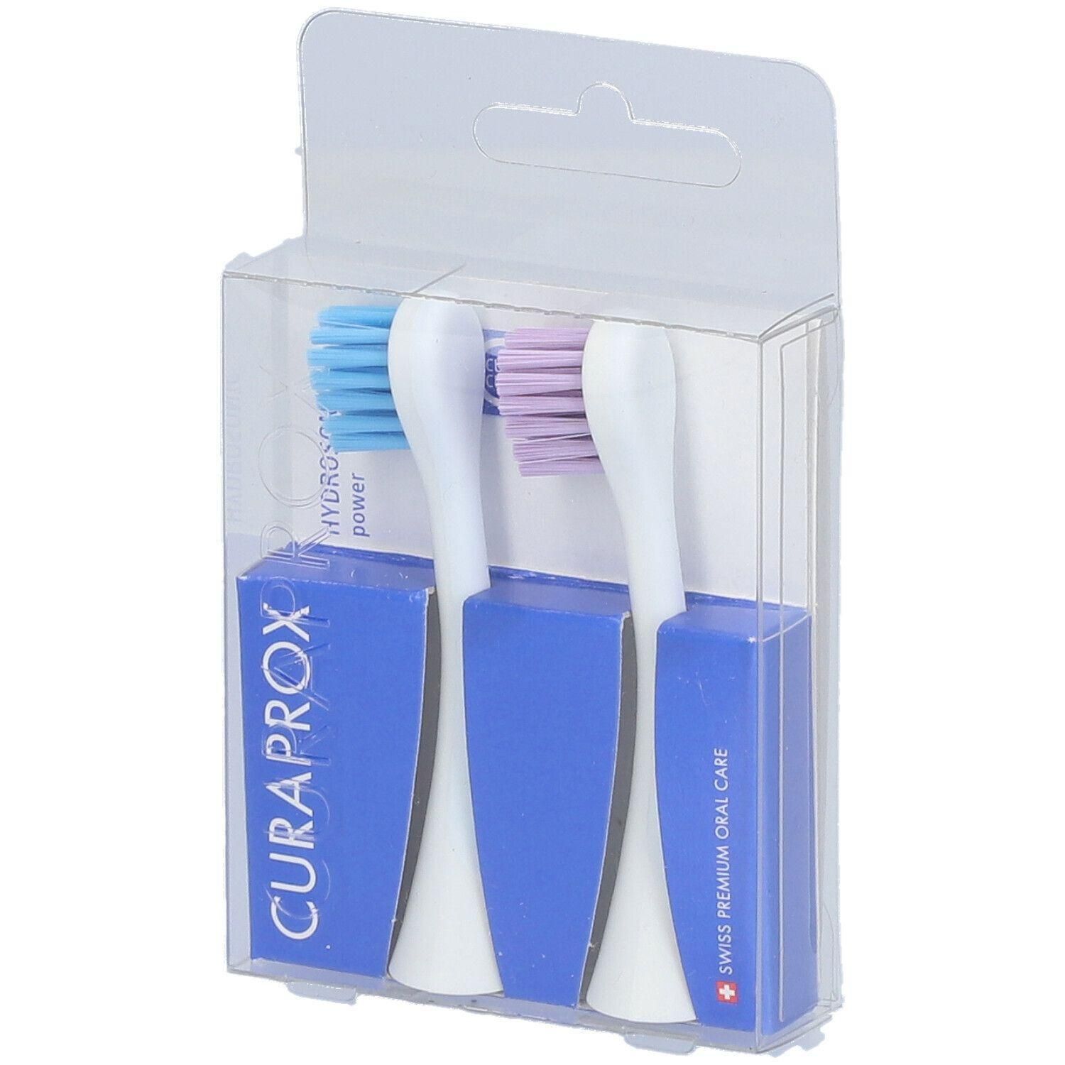 Zwei blaue und lilafarbene Bürstenköpfe in einer transparenten Verpackung. Blaue Verpackung mit CURAPROX-Logo.
