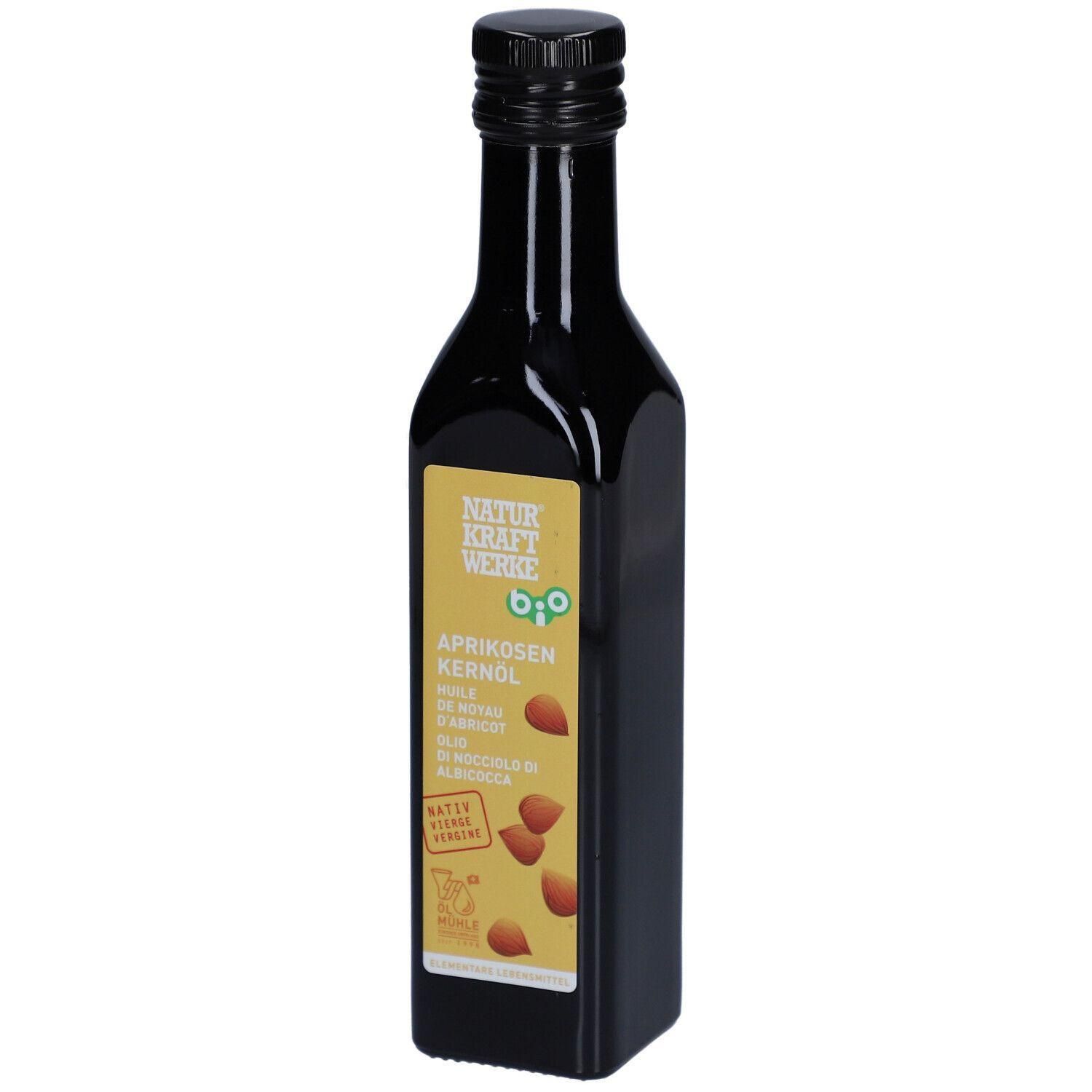Flacon en verre foncé avec bouchon noir et étiquette. Inscription : NATURKRAFTWERKE, huile de noyau d'abricot bio. Avec label bio.