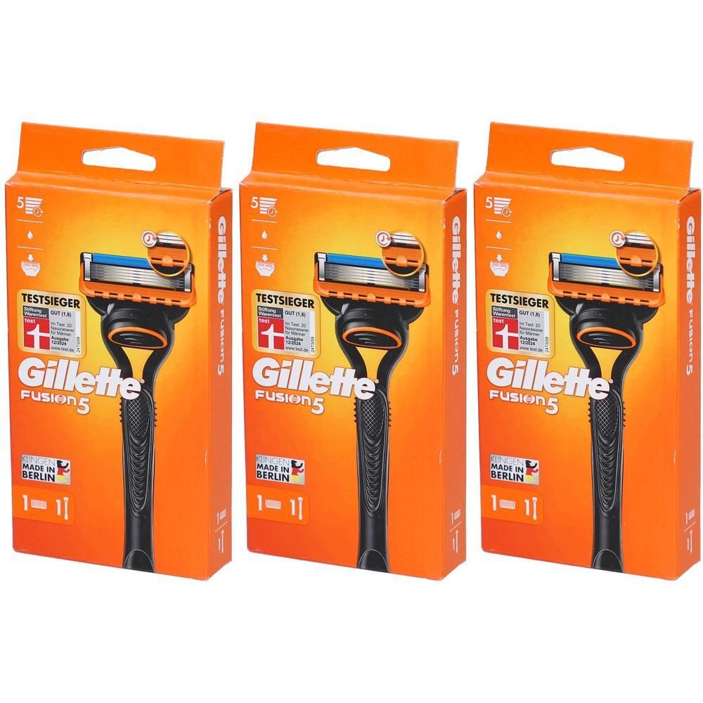 Drei Packungen Rasierer. Orangefarbene Verpackung mit Produktname Gillette Fusion5. Klingen und Griff sichtbar. "TESTSIEGER"-Logo.