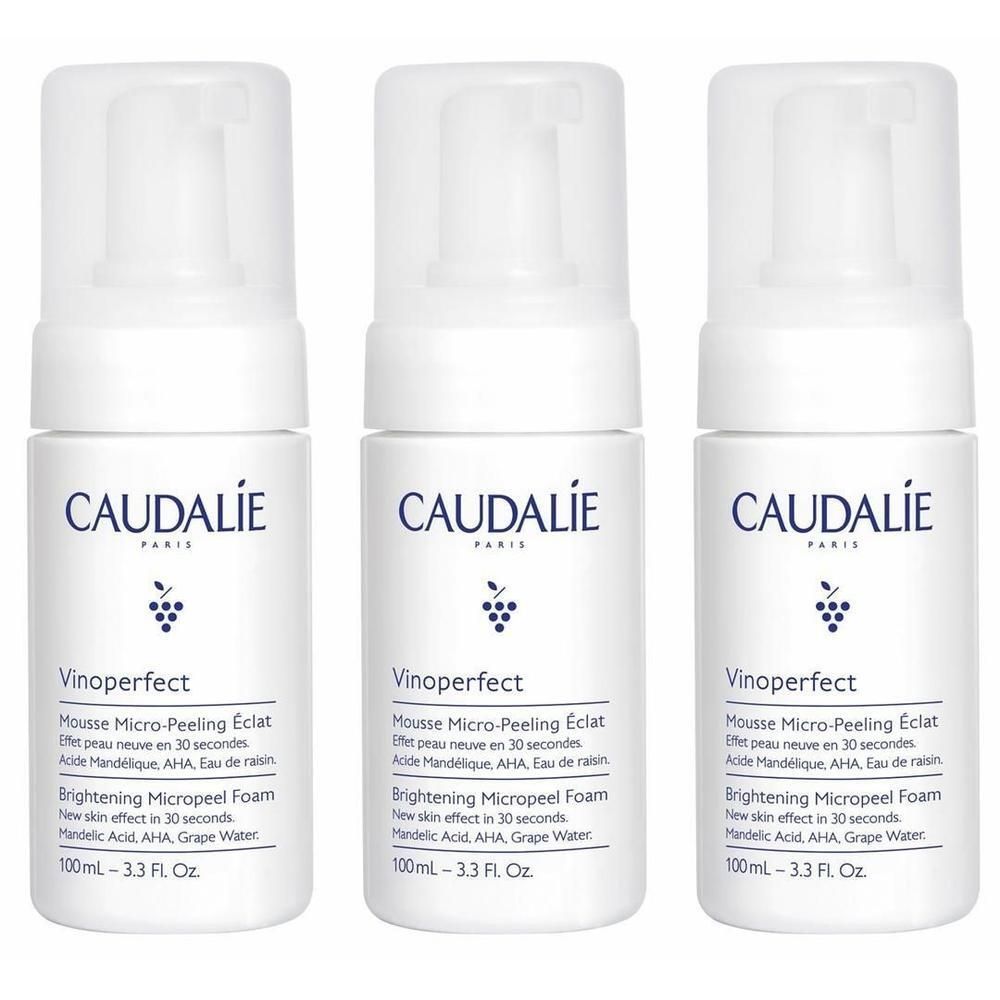 Drei weiße Flaschen mit Sprühkopf. Aufschrift CAUDALIE PARIS, Vinoperfect, Mousse Micro-Peeling Éclat. Enthält AHA und Traubenwasser.
