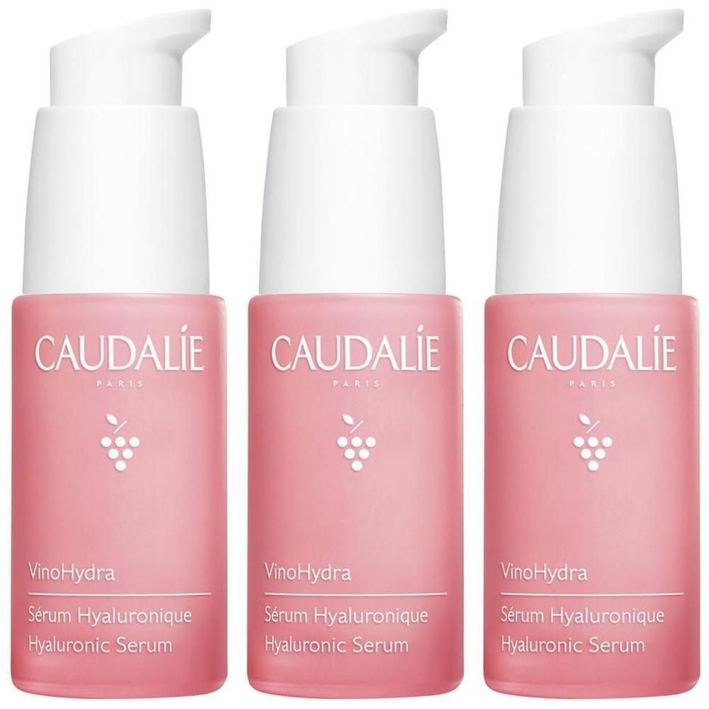 Drei Flaschen CAUDALIE Vinohydra Serum. Rosa Flaschen mit weißem Pumpkopf. Aufschrift: CAUDALIE, VinoHydra, Sérum Hyaluronique, Hyaluronic Serum.
