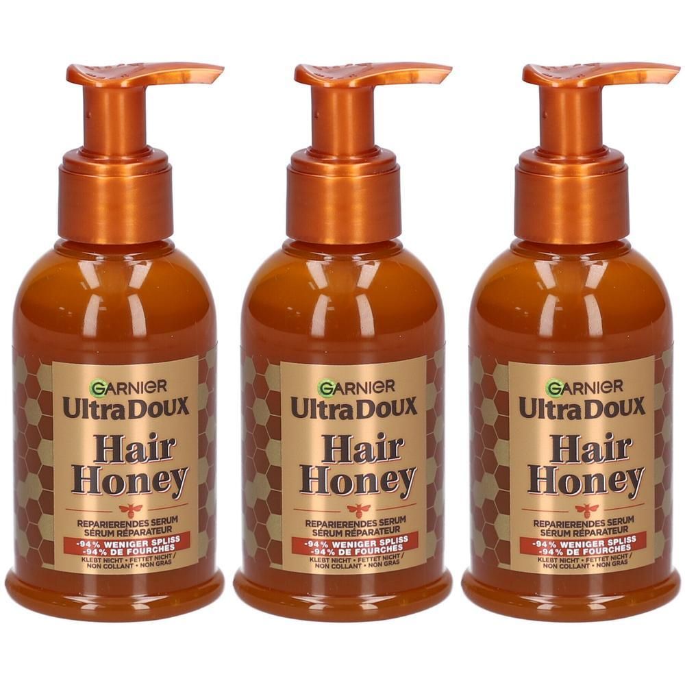 Trois flacons de sérum Garnier Ultra Doux Hair Honey avec distributeurs à pompe.