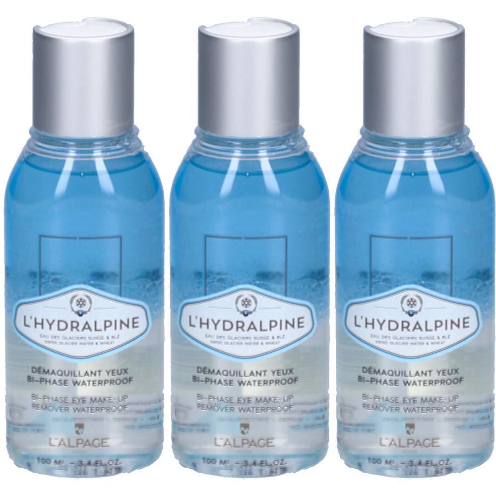 Drei Flaschen L'Hydralpine Augen-Make-up-Entferner. Blaue Flüssigkeit in transparenten Flaschen mit silbernen Deckeln. Aufschrift L'ALPAGE.