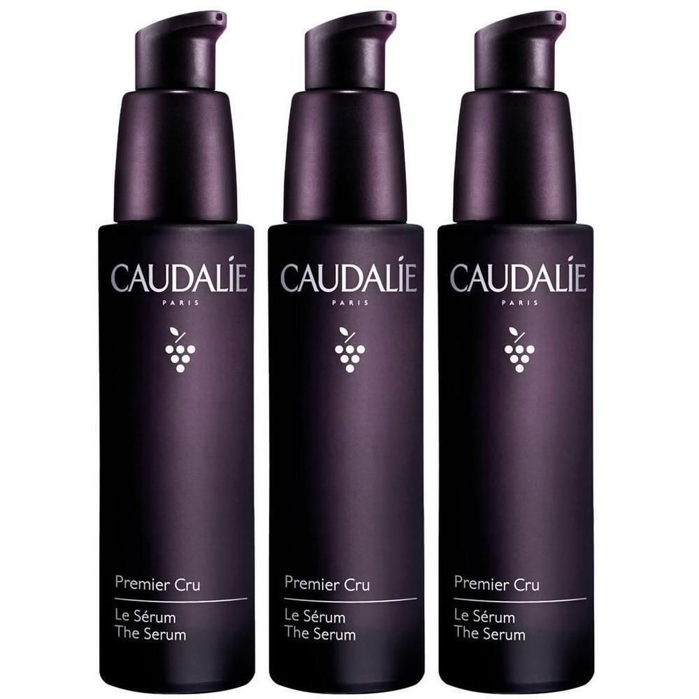 Drei Flakons mit schwarzem Pumpverschluss. Aufschrift CAUDALIE, Premier Cru, Le Sérum, The Serum. Weißes Traubensymbol.