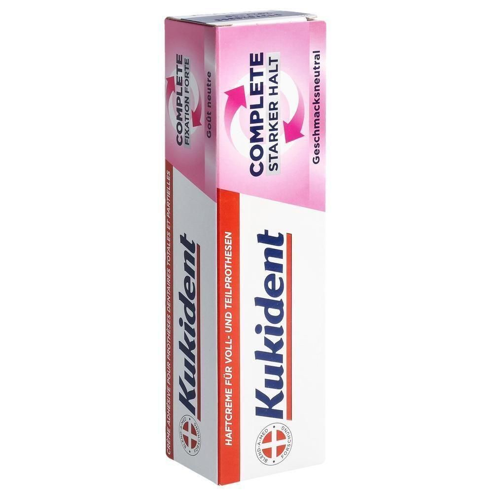 Zahnprothesen-Haftcreme-Tube. Rosa-weiße Verpackung mit Produktnamen und Schriftzügen. "COMPLETE" und "STARKER HALT" sind hervorgehoben.