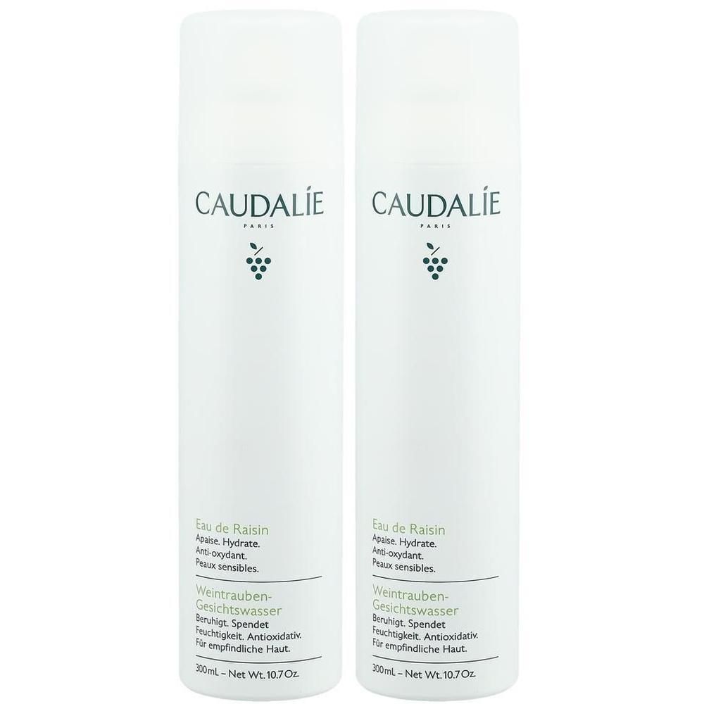 Zwei weiße Flaschen mit Etiketten. Aufschrift: CAUDALIE, Eau de Raisin, Weintrauben-Gesichtswasser. Mit Trauben-Logo.