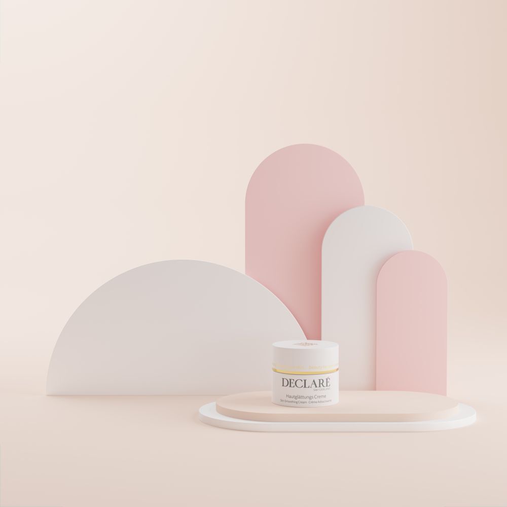 Pot de crème sur plateforme ovale. Couvercle doré. Inscription DECLARE, Crème lissante. Fond beige.