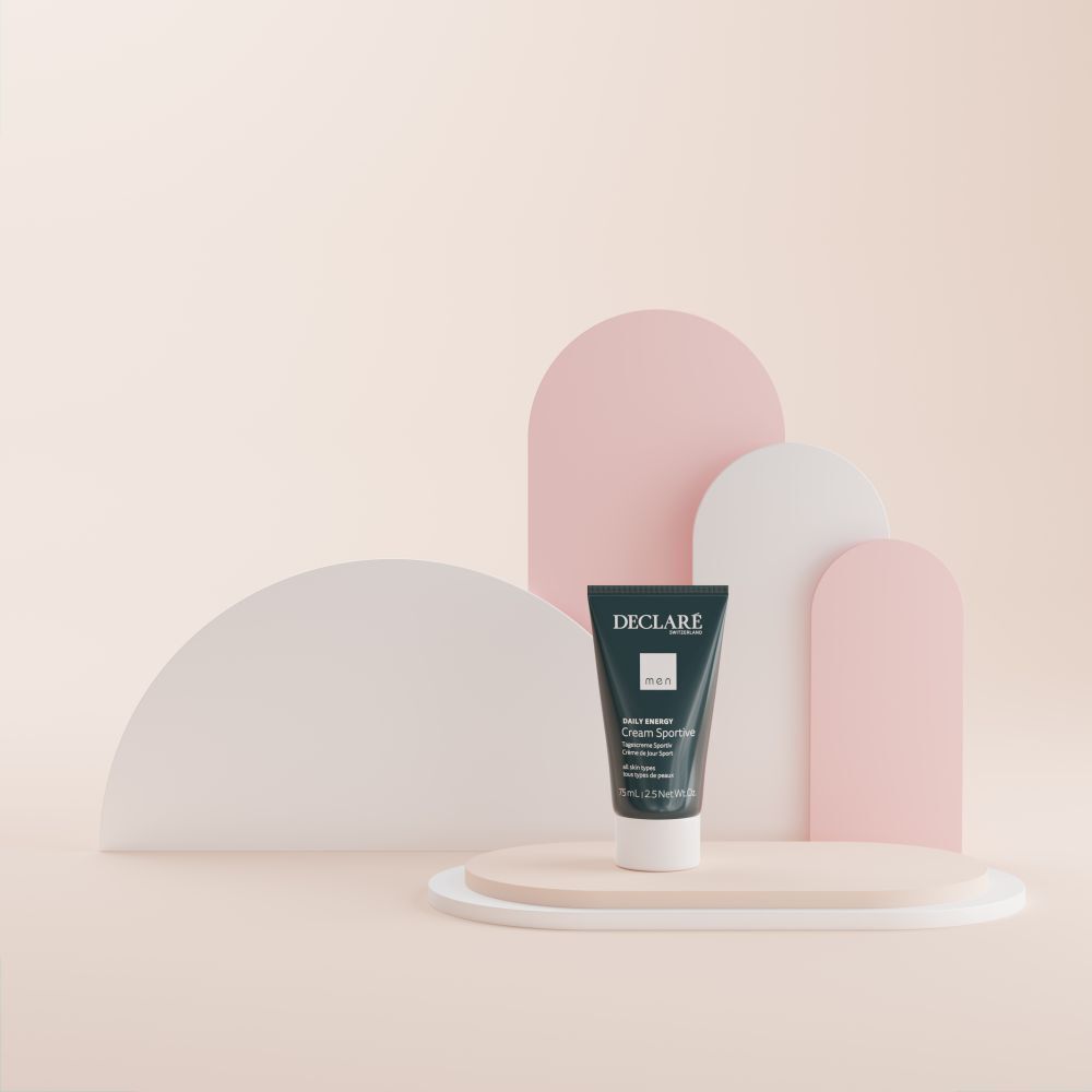 Tubencreme DECLARE Men Tagescreme Sportiv auf Podest. Hintergrund mit rosa, weißen Formen. Produktpräsentation.